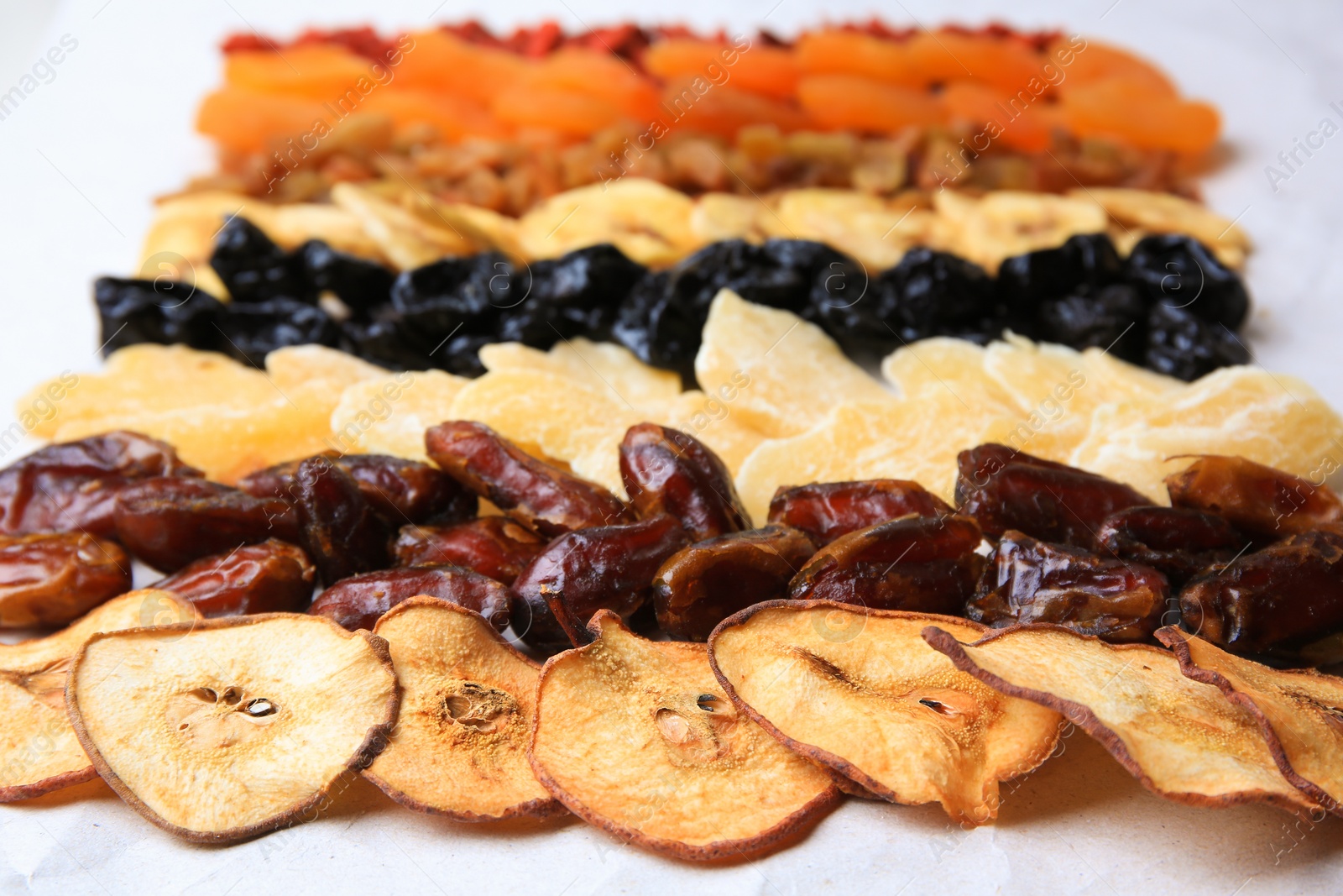 Photo of Different tasty dried fruits on paper, closeup