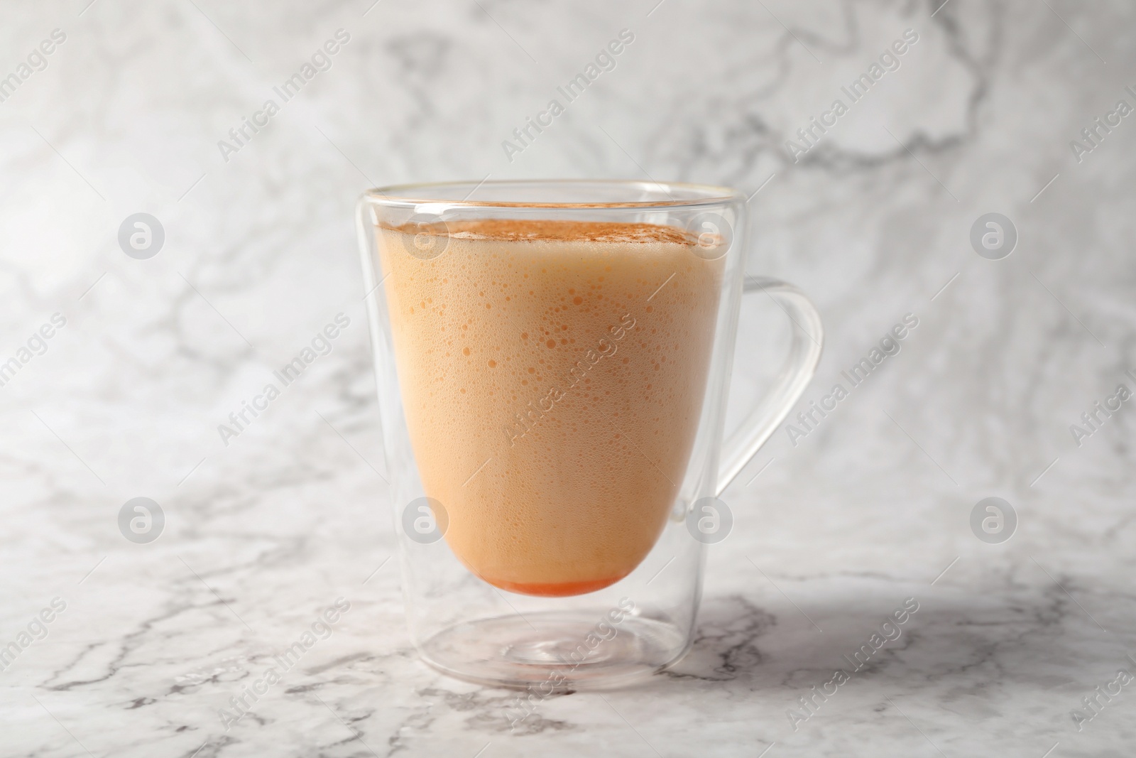 Photo of Glass cup of delicious eggnog on white marble table