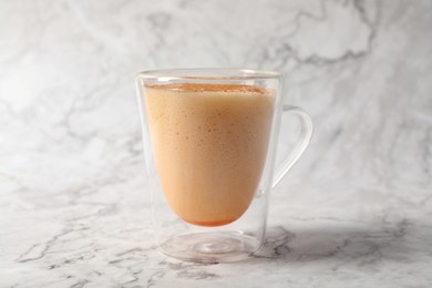 Photo of Glass cup of delicious eggnog on white marble table