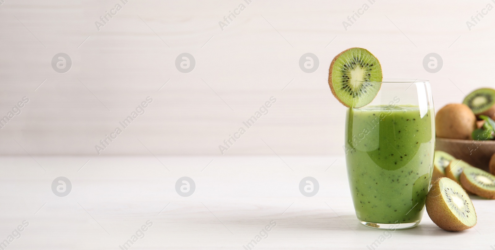 Photo of Delicious kiwi smoothie and fresh fruits on white wooden table. Space for text