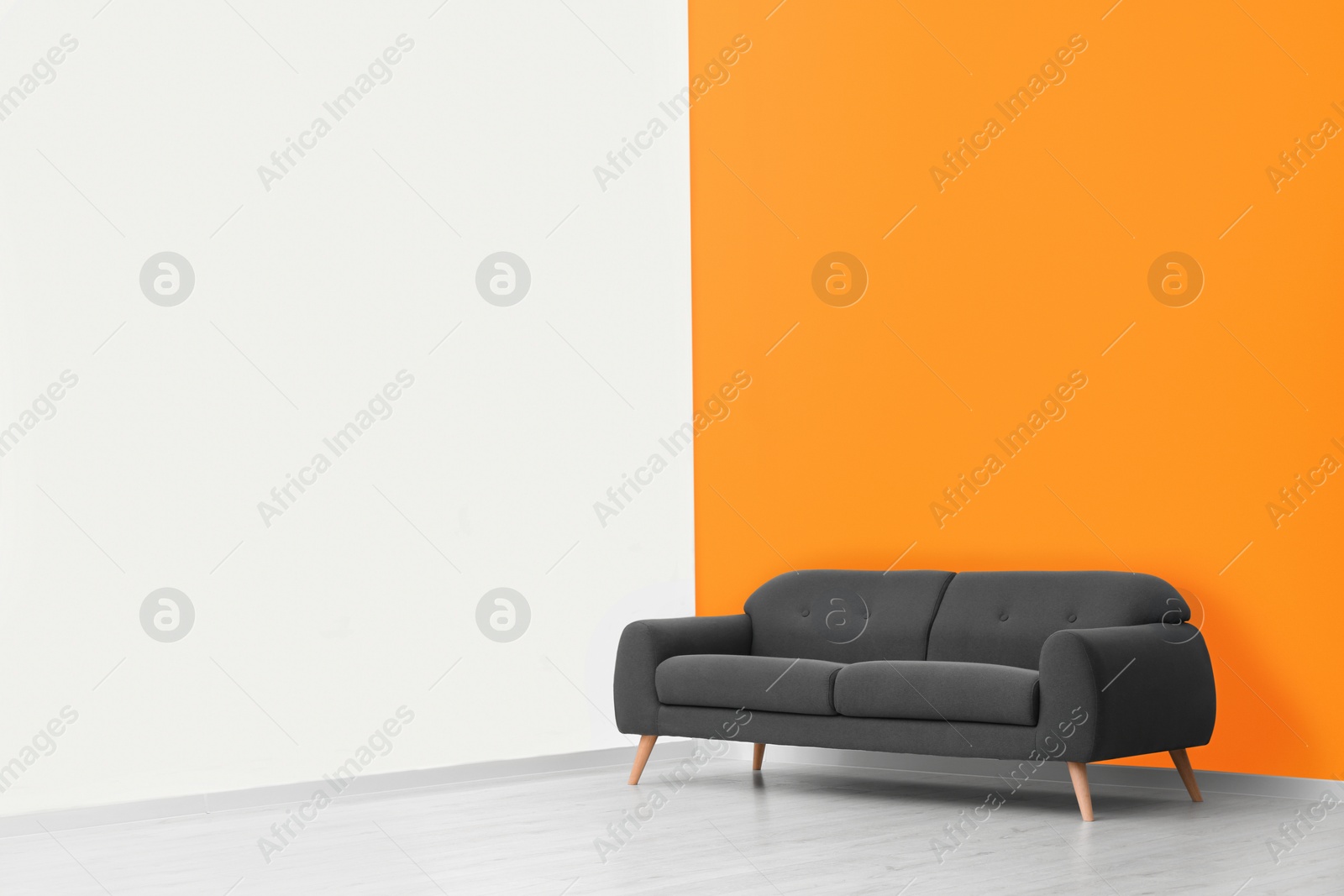 Photo of Stylish room with cosy sofa near orange wall, space for text. Interior design