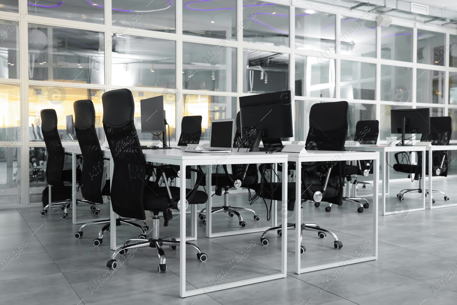 Photo of Stylish interior of open plan office. Workspace with computers, tables and chairs