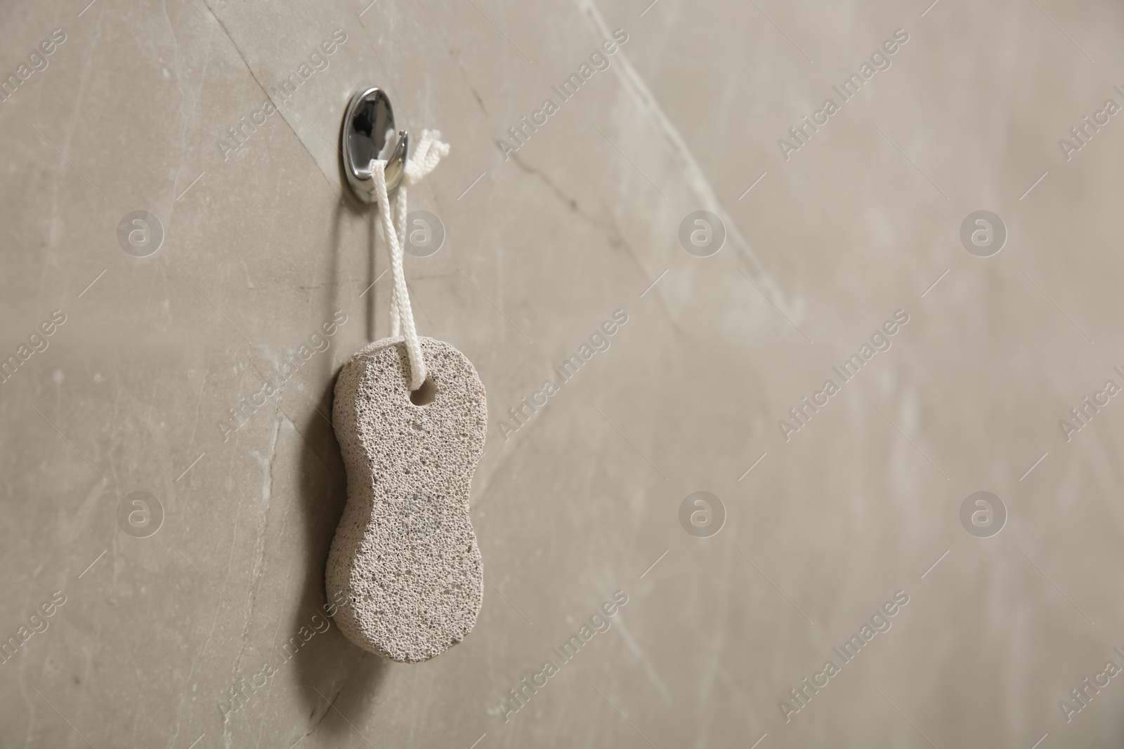 Photo of Pumice stone hanging on grey wall, space for text