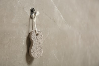 Photo of Pumice stone hanging on grey wall, space for text