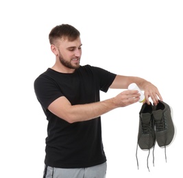 Photo of Young man putting powder freshener into shoes on white background