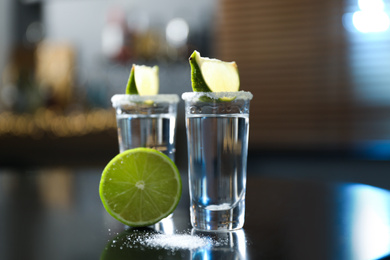 Photo of Mexican Tequila with salt and lime slices on black table at bar