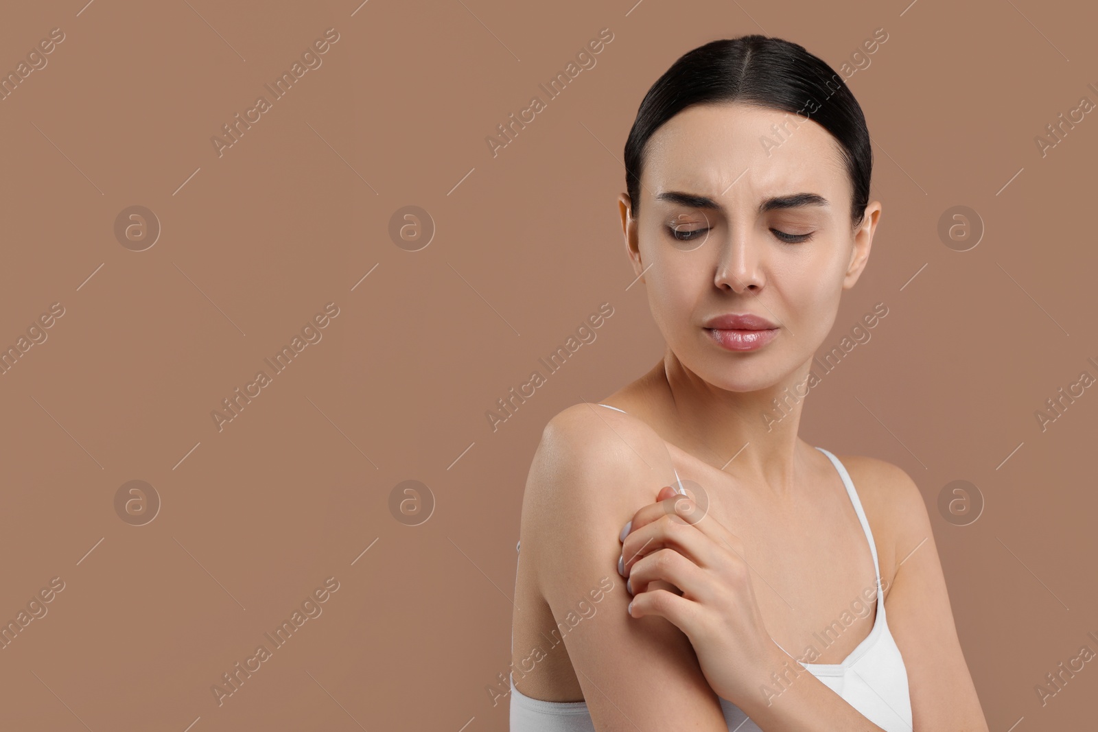 Photo of Woman with dry skin checking her arm on beige background, space for text