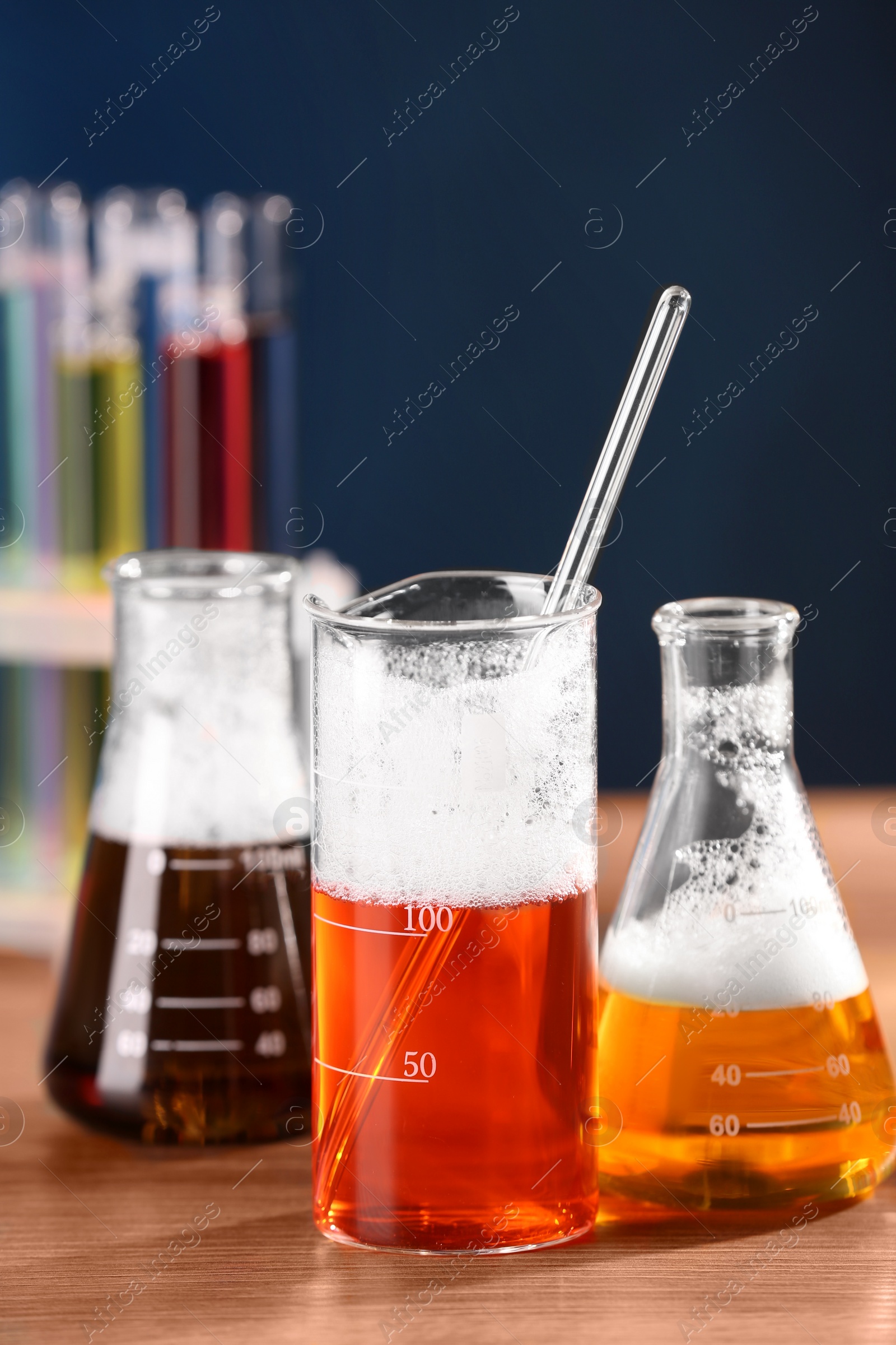 Photo of Laboratory glassware with colorful liquids on wooden table, closeup. Chemical reaction