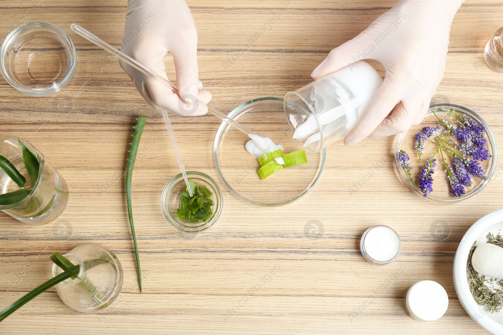 Photo of Scientist developing cosmetic product at wooden table in laboratory, top view