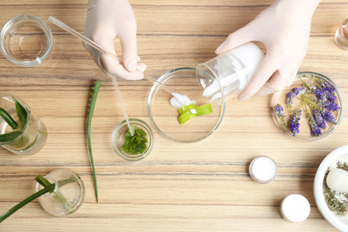 Scientist developing cosmetic product at wooden table in laboratory, top view