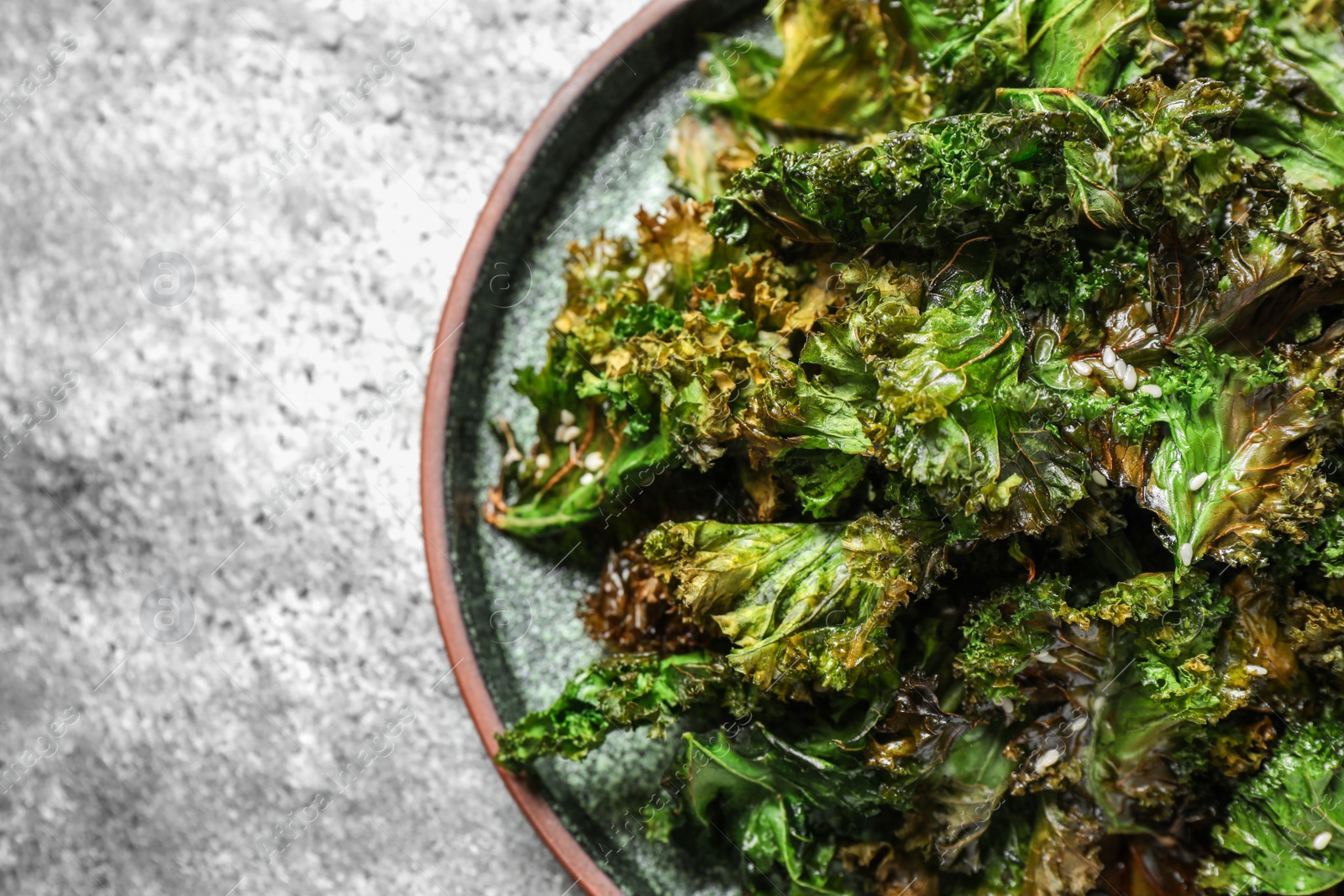 Photo of Tasty baked kale chips on grey table, closeup