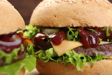 Photo of Delicious cheeseburgers with lettuce, pickle, ketchup and patty, closeup
