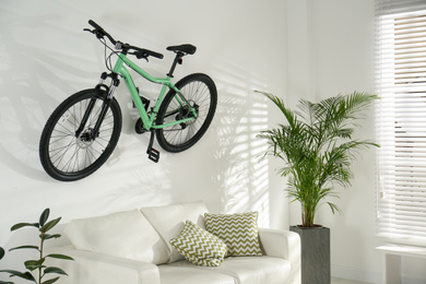 Photo of Stylish living room interior with white sofa and green bicycle