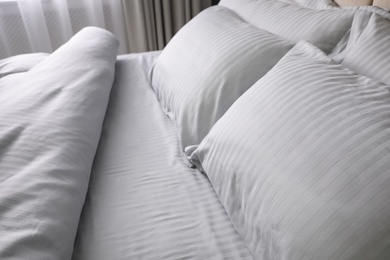 Photo of Comfortable bed with soft blanket and pillows indoors, closeup