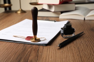 Photo of Document, fountain pen, stamp and inkwell on wooden table, closeup. Notary contract