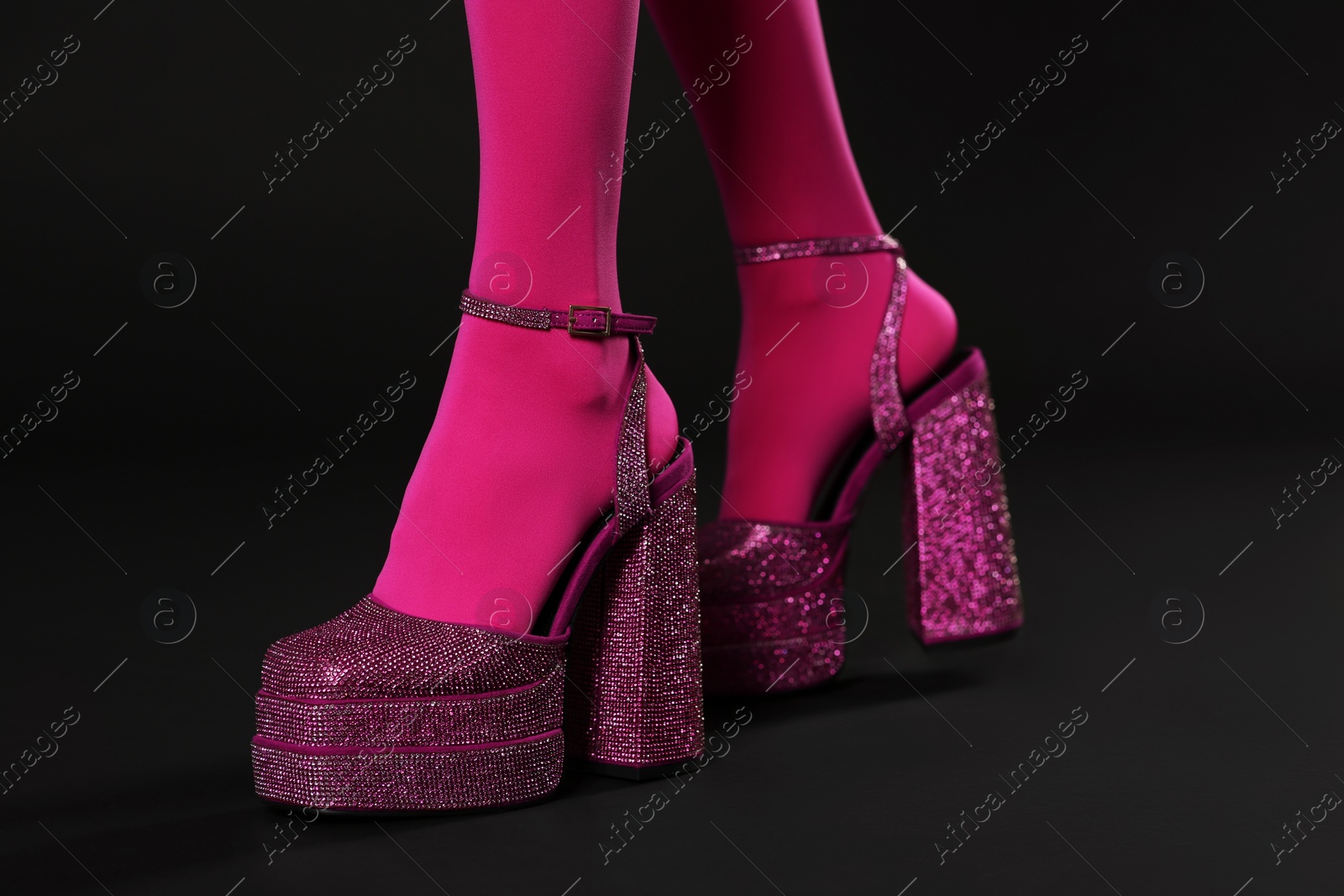 Photo of Woman wearing pink tights and high heeled shoes with platform and square toes on black background, closeup