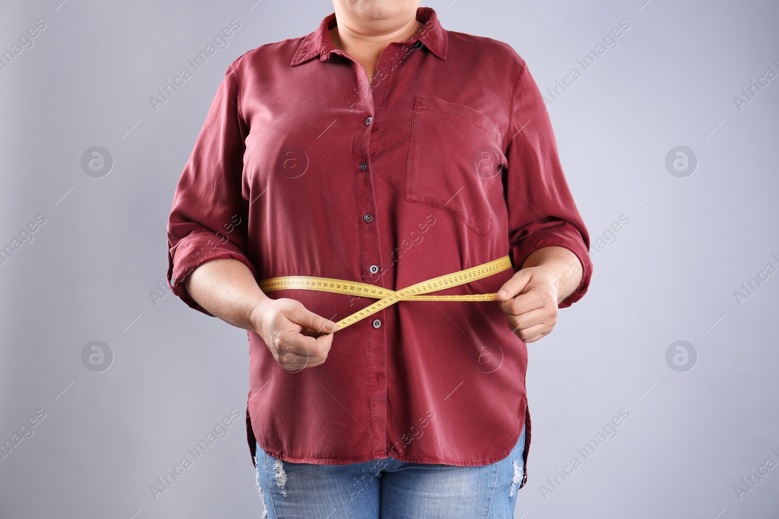 Photo of Fat woman with measuring tape on grey background, closeup. Weight loss