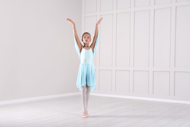 Photo of Beautifully dressed little ballerina dancing in studio. Space for text 