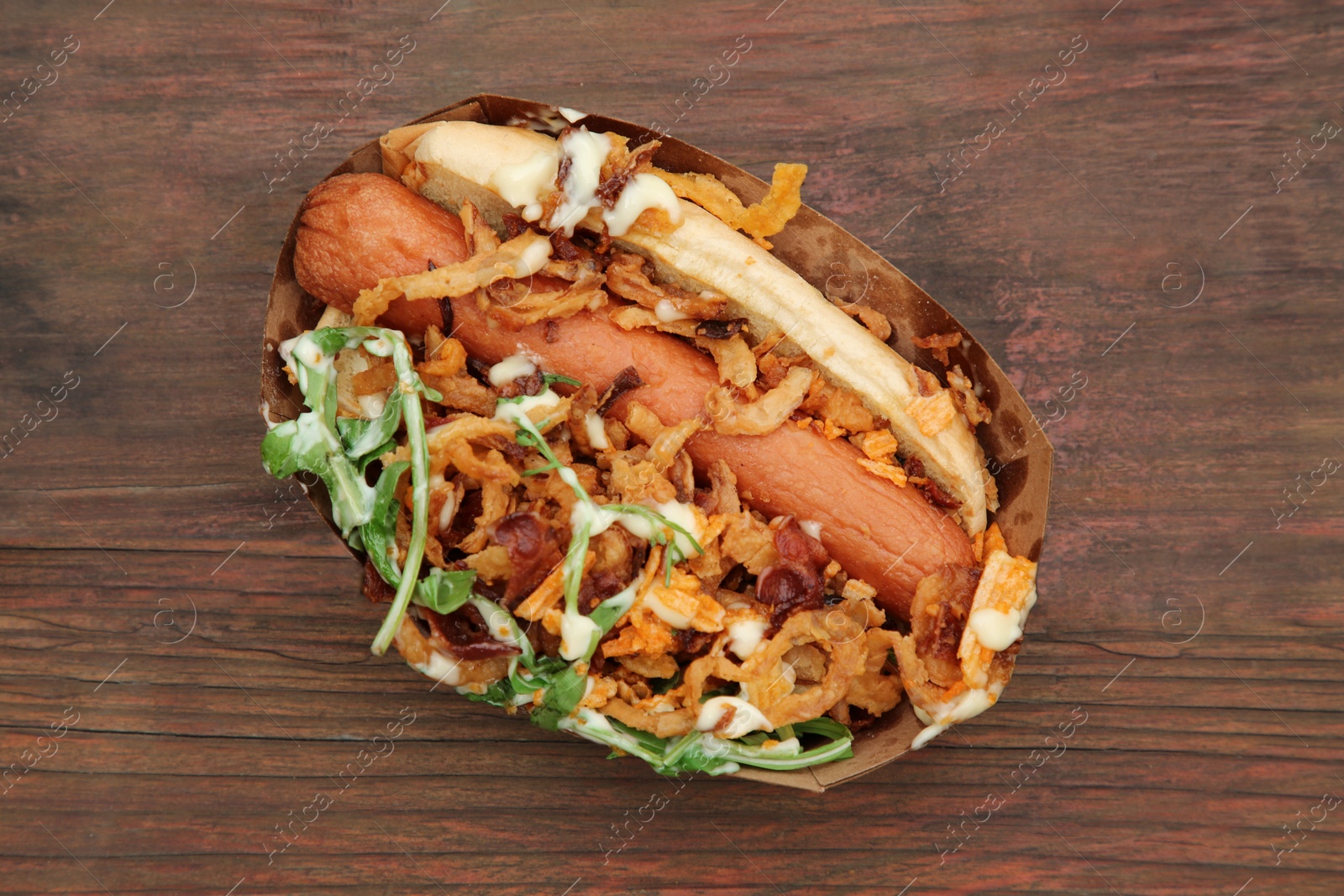 Photo of Fresh delicious hot dog on wooden table, top view