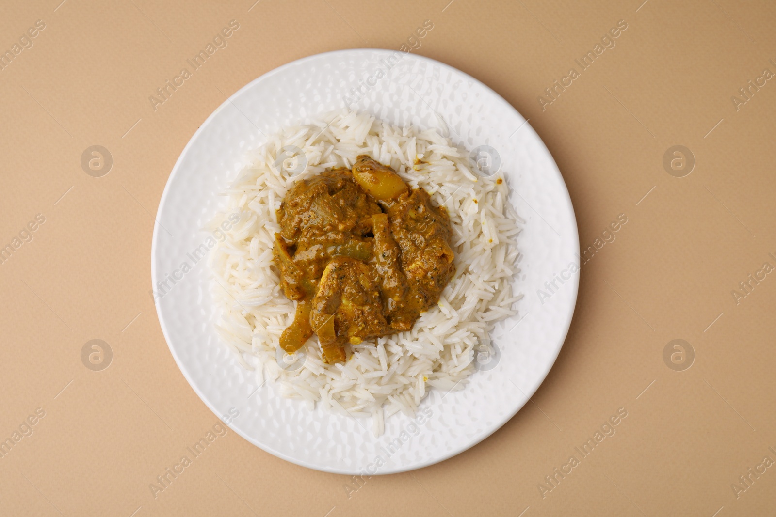 Photo of Delicious chicken curry with rice on beige background, top view