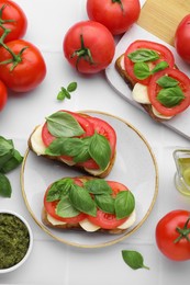 Photo of Delicious Caprese sandwiches with mozzarella, tomatoes, basil and other ingredients on white table, flat lay