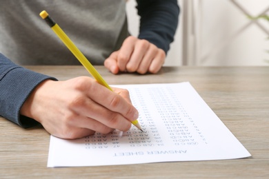 Student filling answer sheet at table, closeup