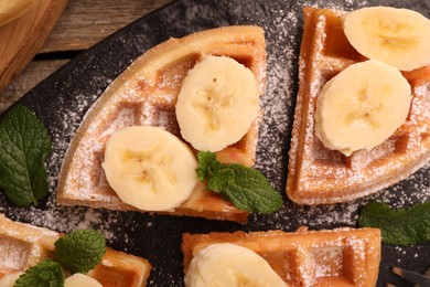 Tasty Belgian waffles with banana and mint on table, top view