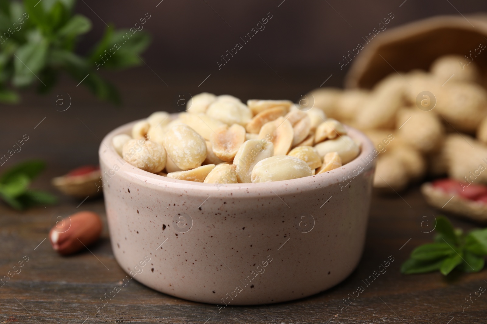 Photo of Fresh peeled peanuts in bowl on wooden table, closeup