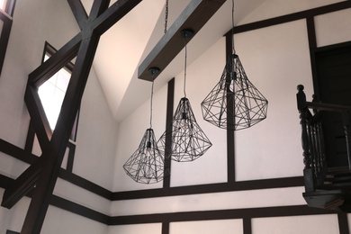 Photo of Stylish metal pendant lamps with light bulbs indoors