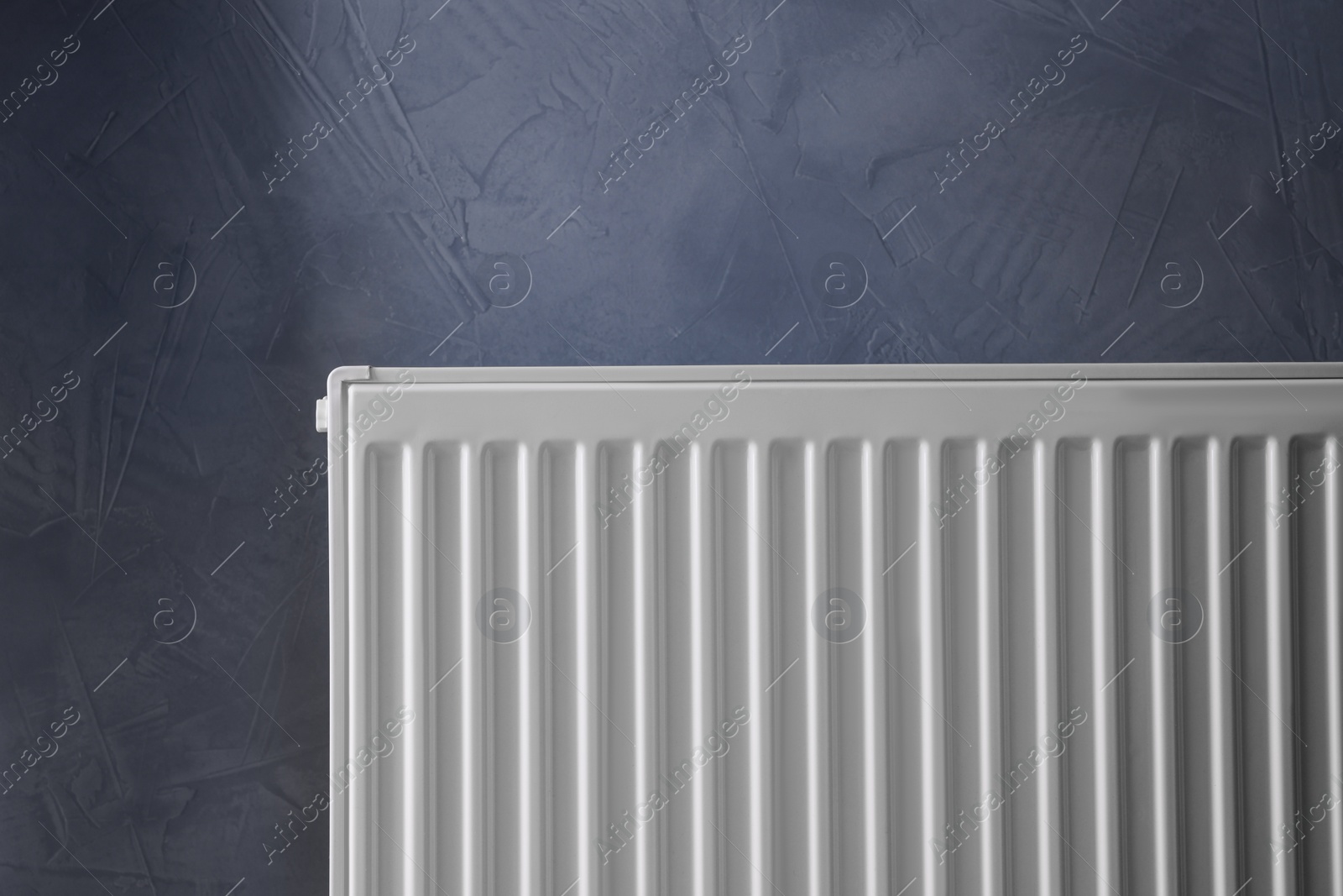 Photo of Modern radiator on grey wall. Central heating system