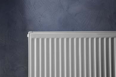 Photo of Modern radiator on grey wall. Central heating system