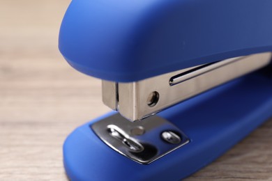 Photo of One blue stapler on wooden table, closeup