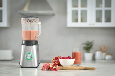 Blender with tasty smoothie and ingredients on white marble table in kitchen