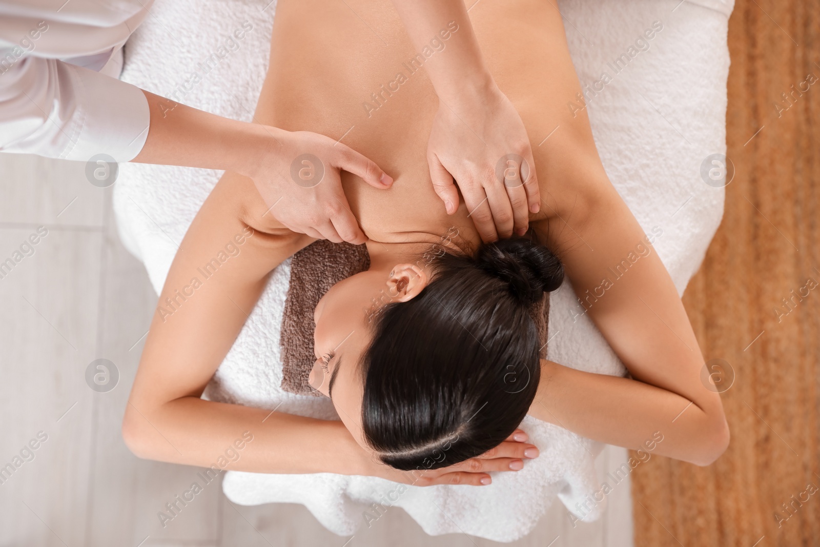 Photo of Young woman having professional massage in spa salon, top view