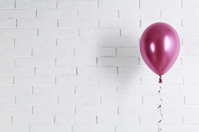 Photo of Bright balloon near brick wall, space for text. Party time