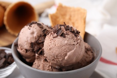 Bowl of tasty ice cream with chocolate chunks on table, closeup