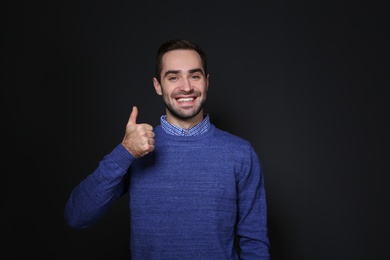 Photo of Man showing THUMB UP gesture in sign language on black background
