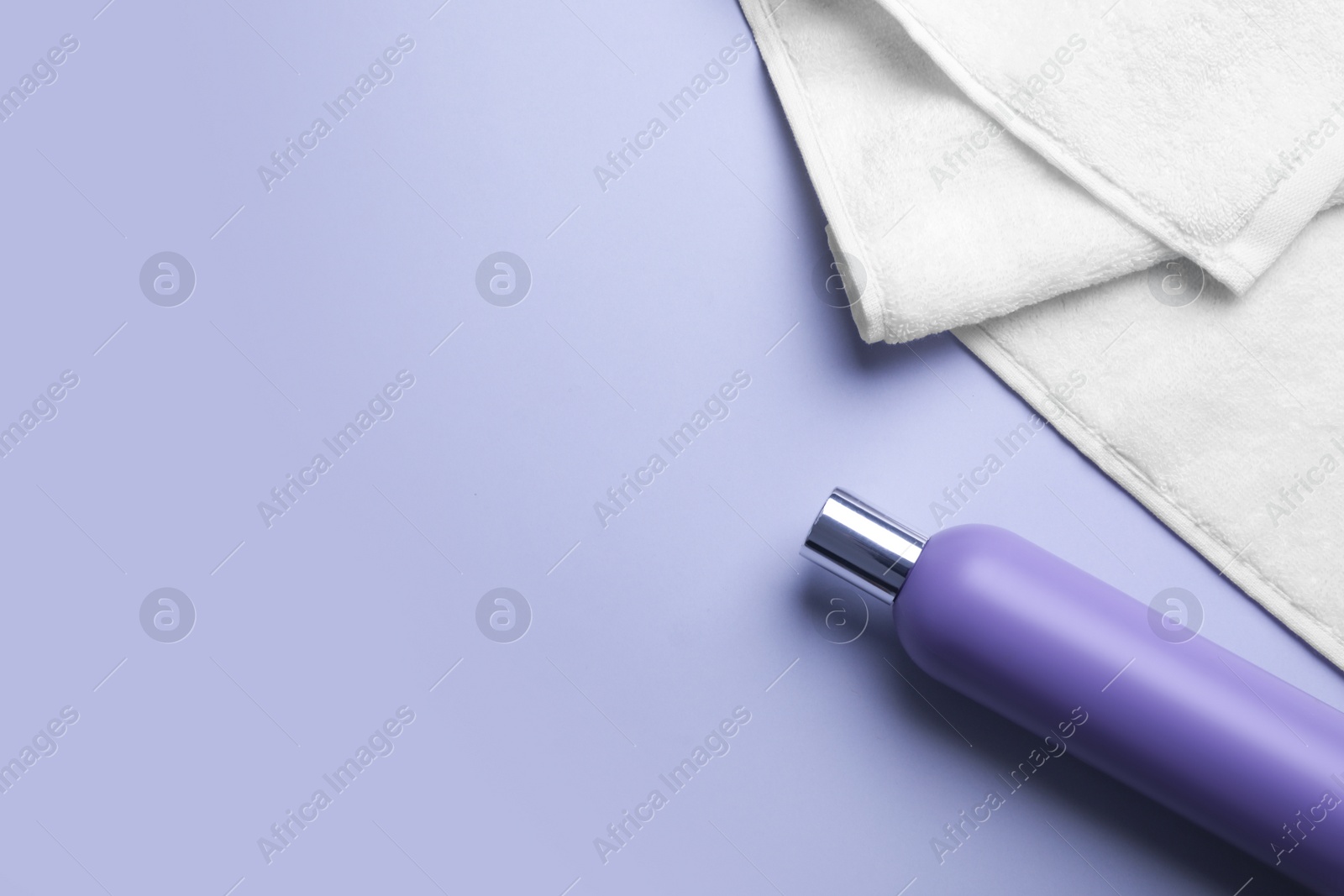 Photo of Bottle of shampoo and towel on color background, top view with space for text