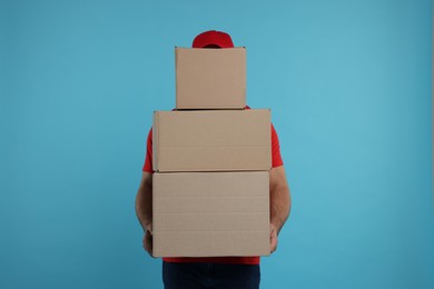 Photo of Courier with stack of parcels on light blue background