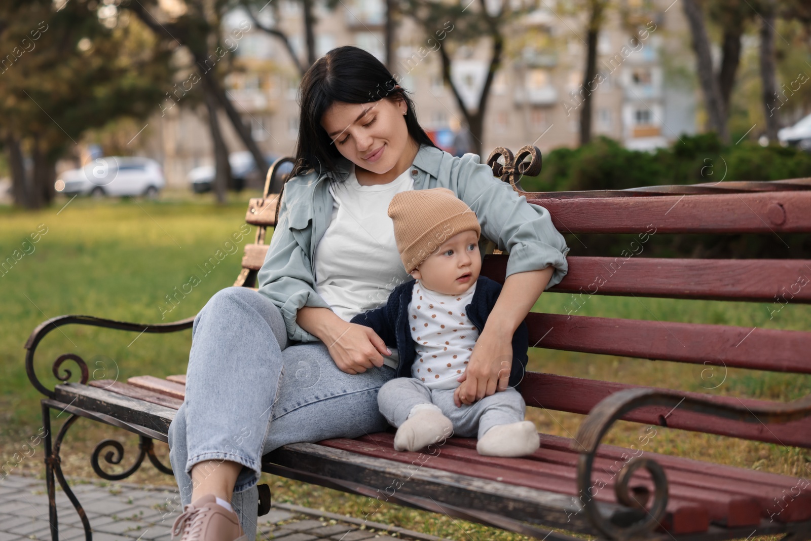 Photo of Family portrait of mother and her baby on bench in park