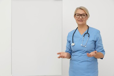 Photo of Professional doctor explaining something near flipchart, space for text