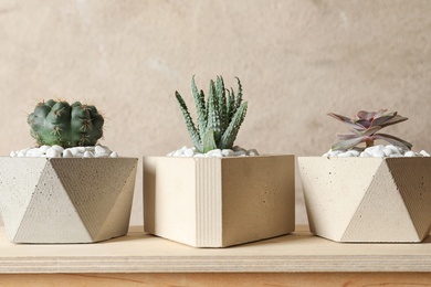 Beautiful succulent plants in stylish flowerpots on wooden table against brown background. Home decor