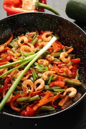 Photo of Shrimp stir fry with vegetables in wok and ingredients on black table