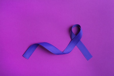 Purple awareness ribbon on color background, top view