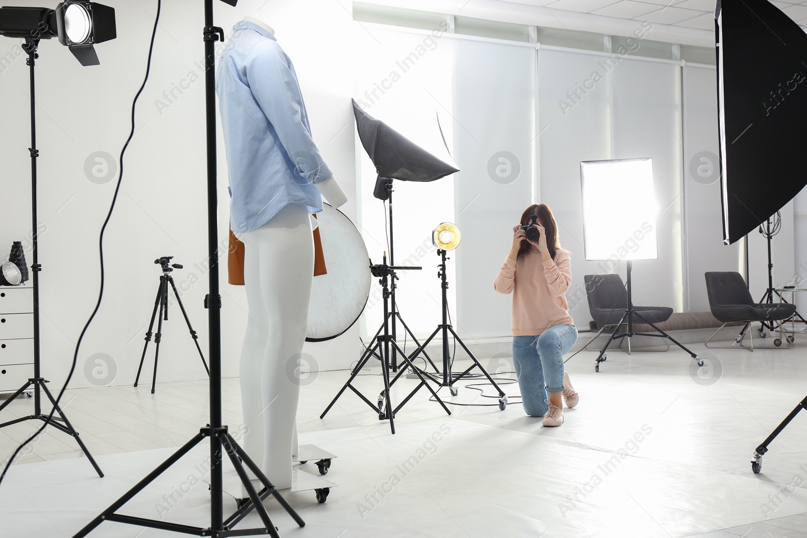 Photo of Professional photographer taking picture of ghost mannequins with modern clothes in photo studio