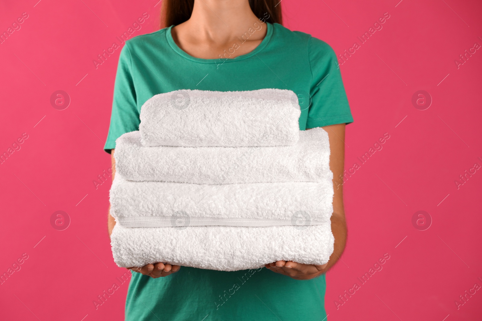 Photo of Woman holding fresh towels on pink background, closeup