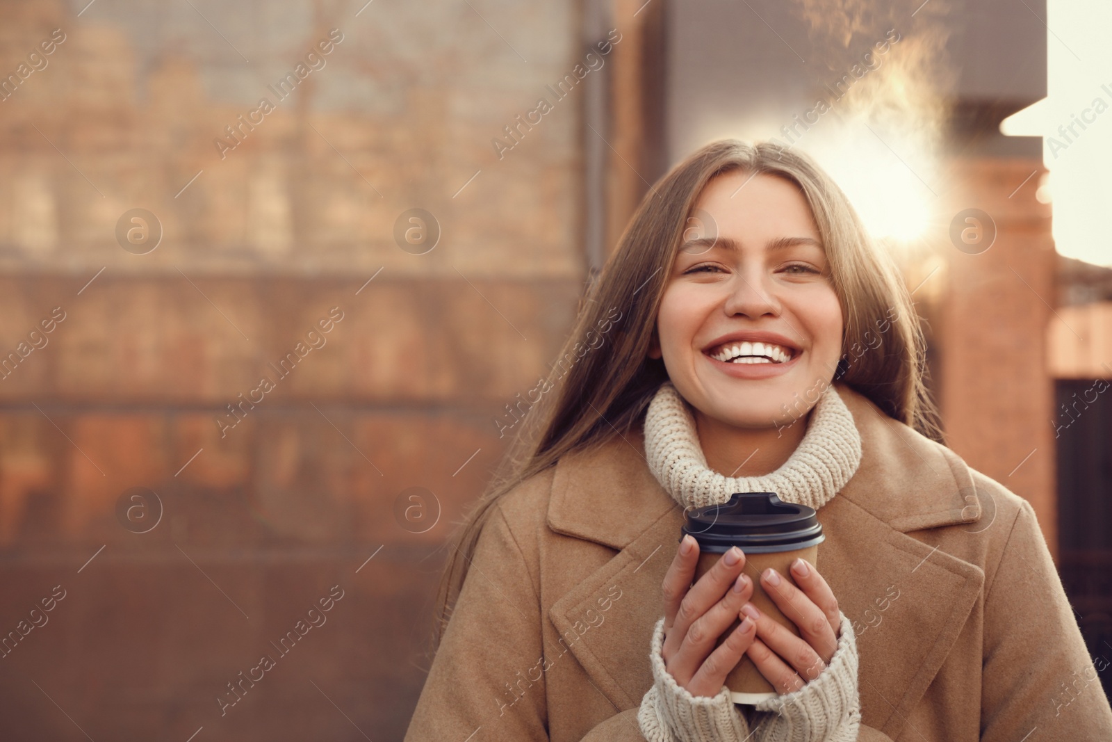 Photo of Young woman with cup of coffee on city street in morning