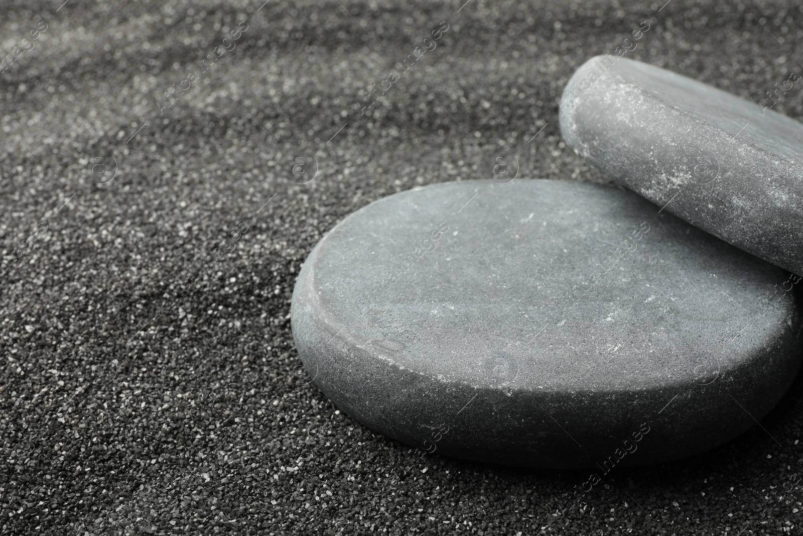 Photo of Presentation of product. Stone podiums on black sand, closeup. Space for text