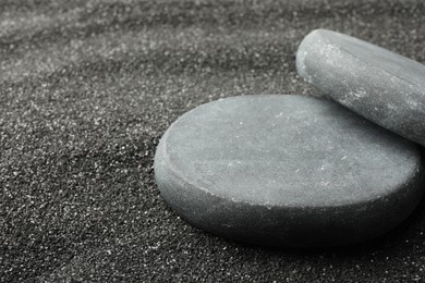 Presentation of product. Stone podiums on black sand, closeup. Space for text