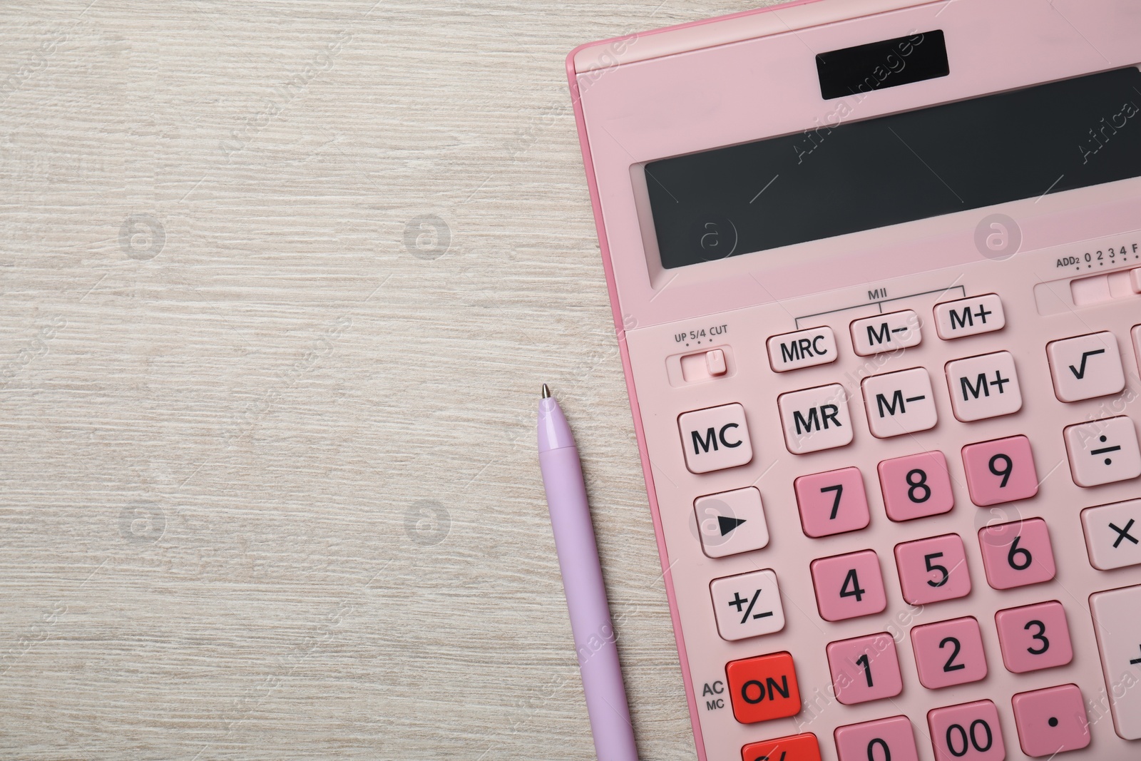 Photo of Calculator and pen on light wooden table, top view. Space for text